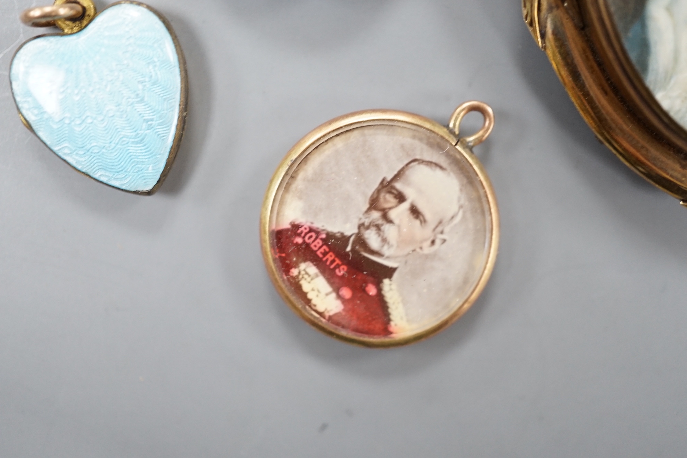 A 19th century yellow metal miniature oval portrait mourning brooch, 54mm, two enamelled lockets(a.f.) and one other small pendant.